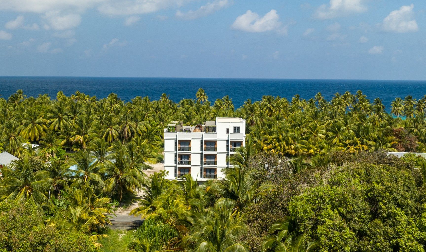Aerial view of Ataraxis Hotel in Fuvahmulah, Maldives - lush tropical rooftop and guests enjoying the terrace